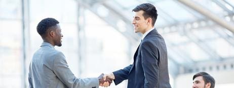 Two people shaking hands in a business setting.