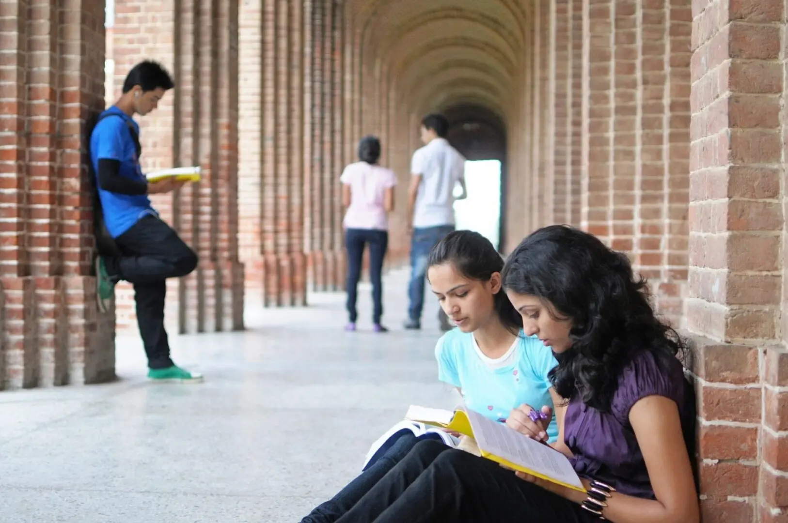 A Group Of People Studying In A Corridor